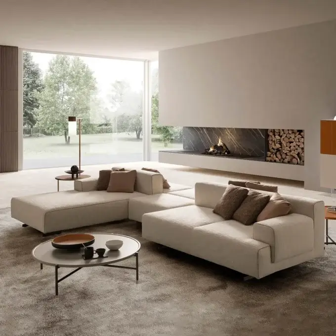 Contemporary living room with a light beige modular sofa, black metal coffee table, slate fireplace, brass floor lamp, and wooden slat wall.