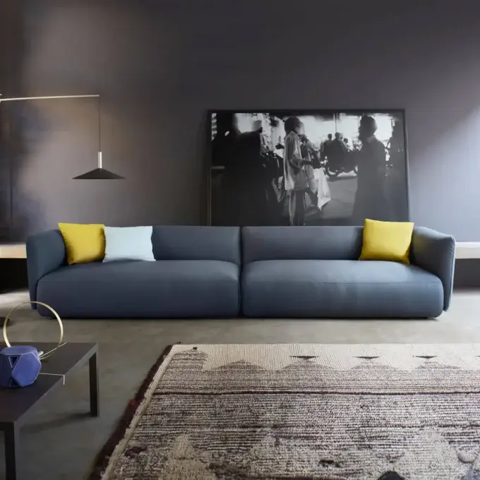 Modular sofa, dark gray fabric, low profile with wide cushions, paired with mustard & light gray pillows, black & white photograph backdrop.