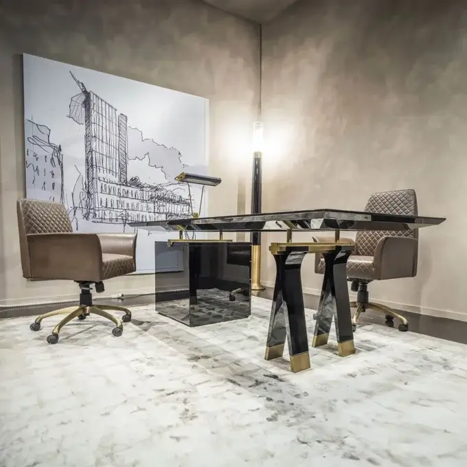 Black glass desk with gold metal base, flanked by brown leather armchairs, and a gold floor lamp, on a marbled rug.