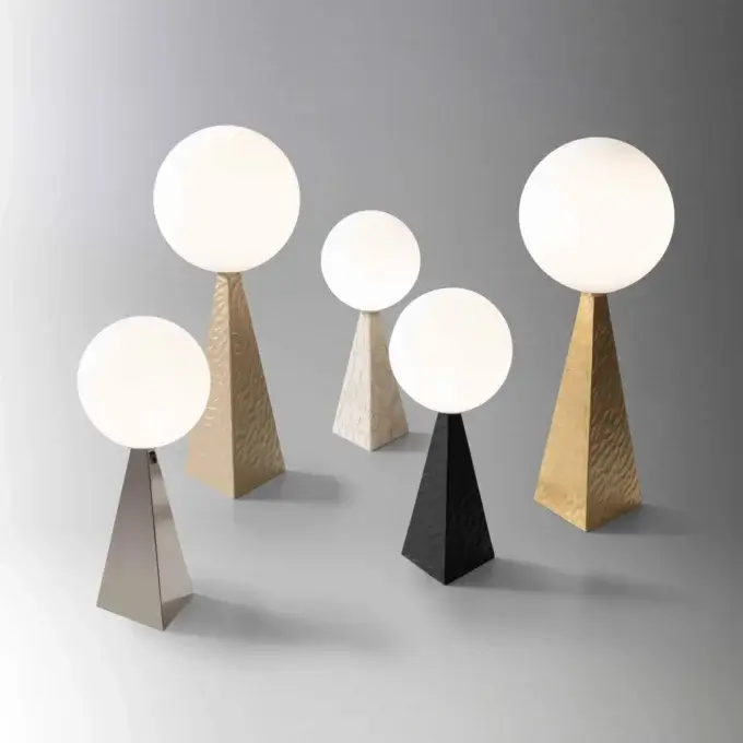 Stillux lamps with opaque white globes on textured gold, silver, black, and marble pyramid bases, studio lighting.