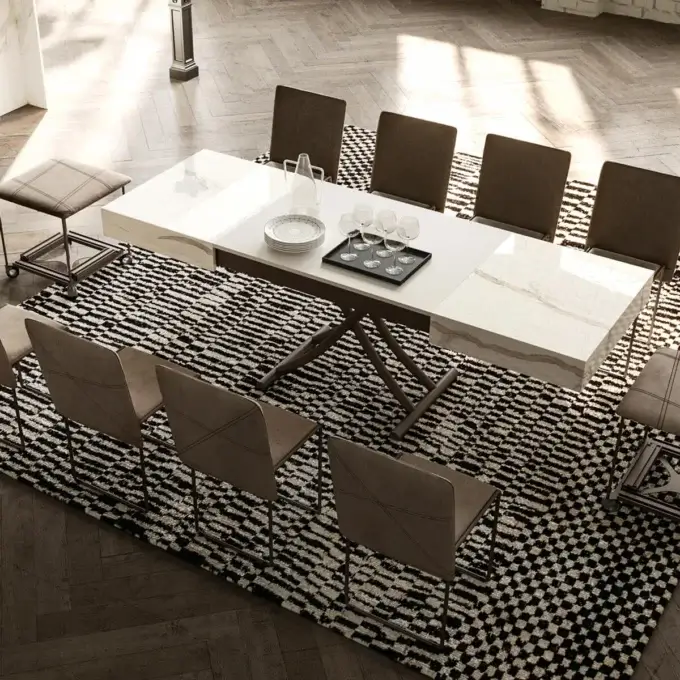 Dining table with white marble top and dark metal base, surrounded by eight brown upholstered chairs on a patterned rug.