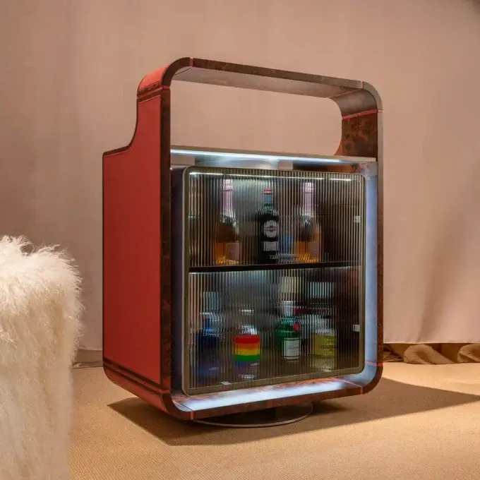 Bar cabinet, wood and glass, curved design with red trim, revealing illuminated bottles inside, against a neutral wall.