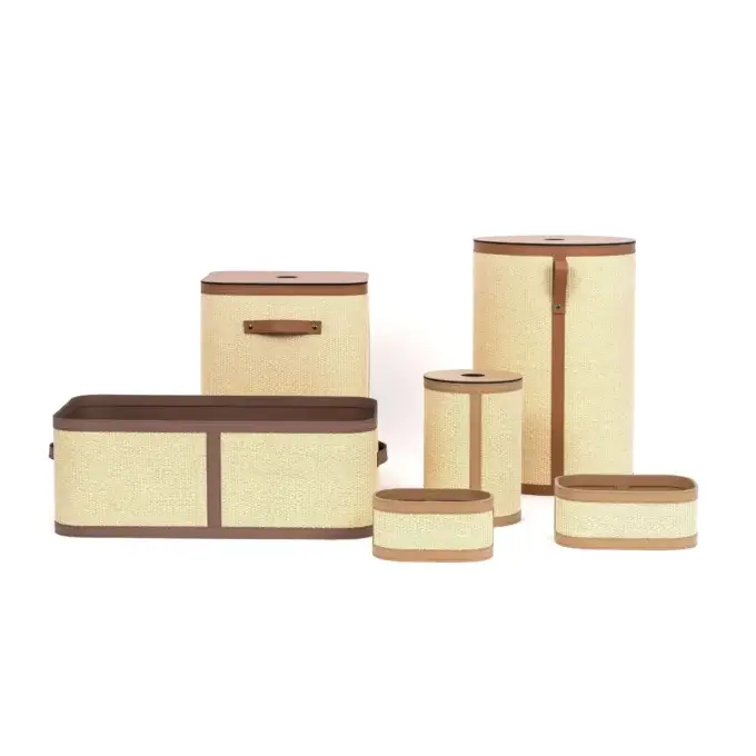 Woven storage containers in beige seagrass with dark brown leather trim, featuring cylindrical and rectangular geometric shapes, studio shot.