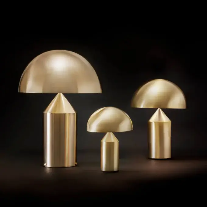 Cassoni Oluce Atollo Metal Table Lamps in brass, featuring dome shades and cylindrical tapered bases, arranged against a dark gray background.