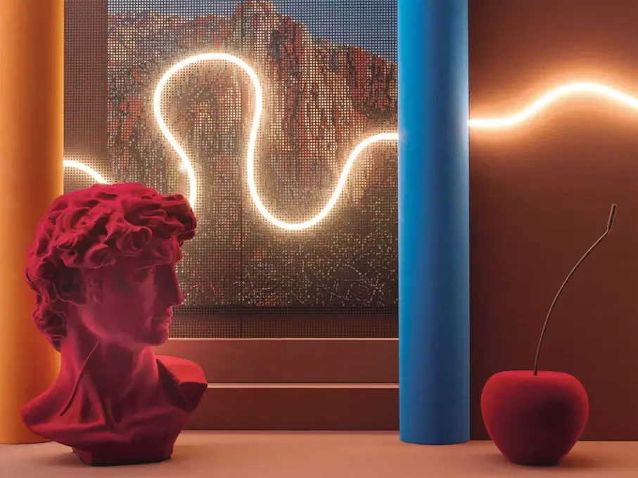 Still life with red David bust, blue column, and cherry, lit by neon against terracotta wall and grid window backdrop.