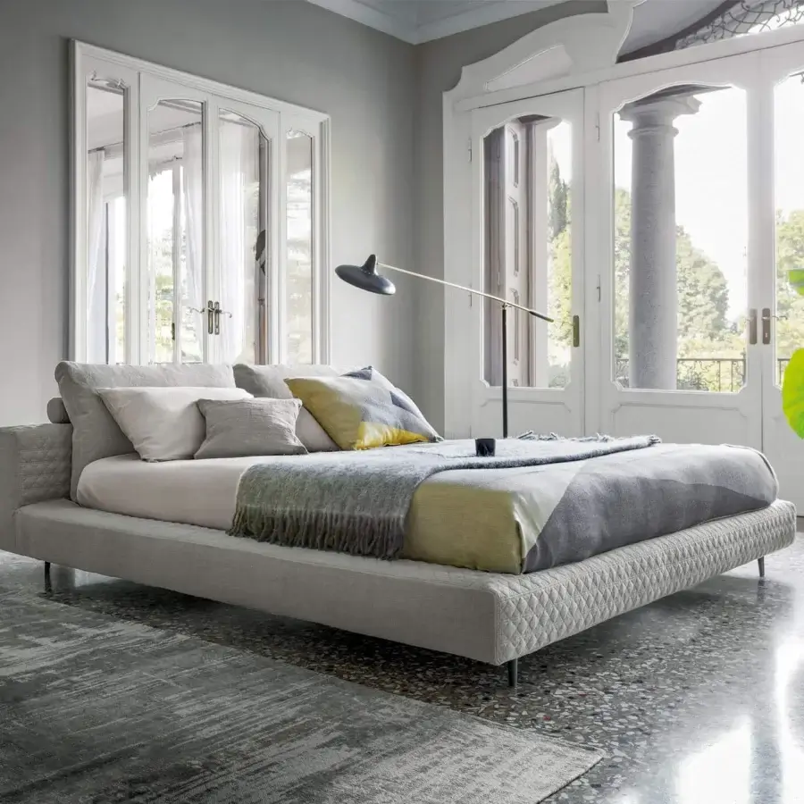 Sophisticated Bonaldo Owen bed with quilted light gray fabric and coordinating light beige surfaces built with dark painted metal feet