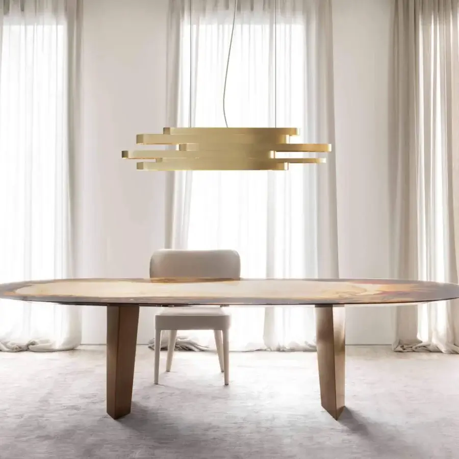 Lavish Rugiano Pedro table with oval glass exhibiting gold, brown and white design atop bronzed brass legs