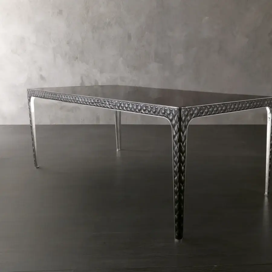 Elegant Rugiano Alexander table with quilted dark leather, curved legs and bright metal accents