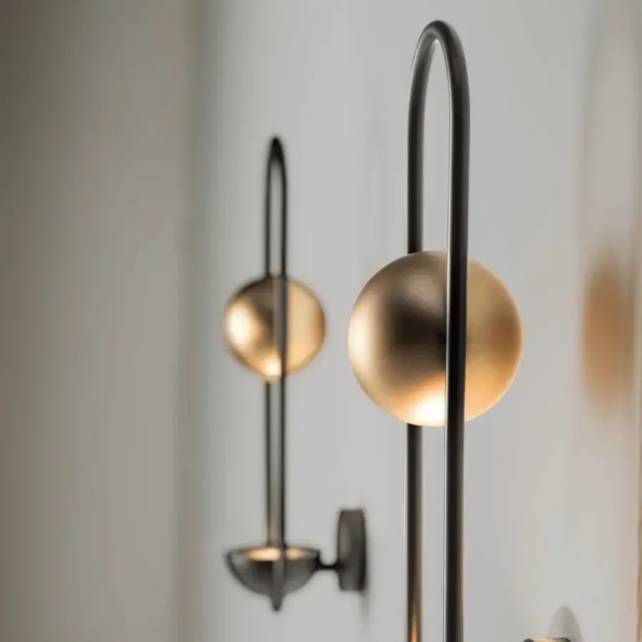 Exclusive Masiero Luppiter wall lamp with curved dark gray metal support and golden metal sphere emitting soft light