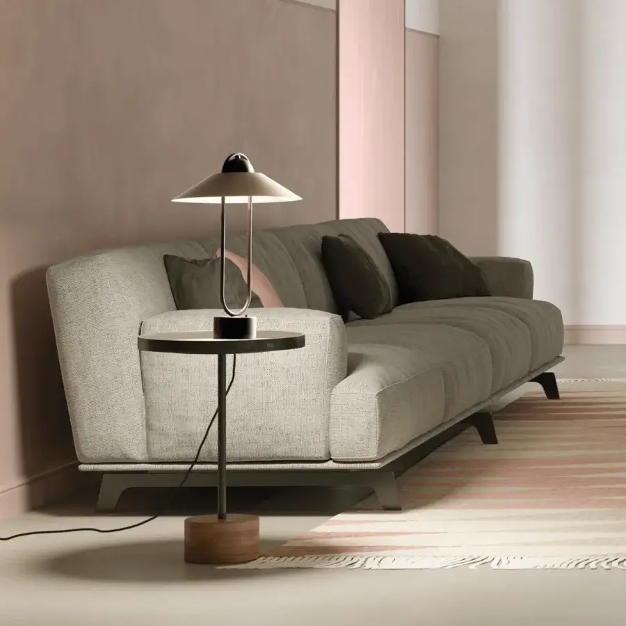 Masiero Lúppiter table lamp, brushed silver, conical shade on black stem with wooden base, next to grey pleated sofa.