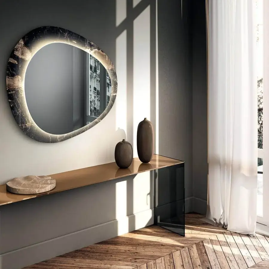 Elegant Lago Era mirror with organic oval silhouette in XGlass evoking dark veined stone and built-in LED lighting