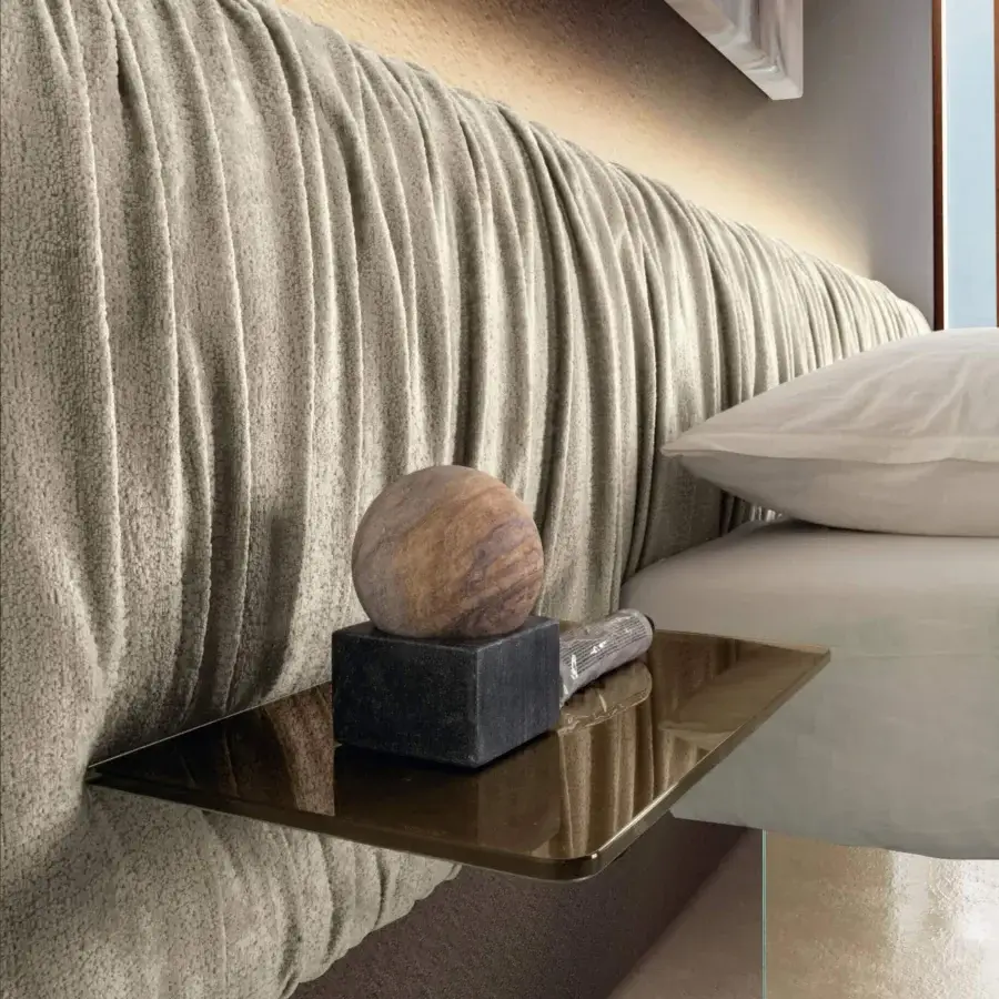 Elegant Lago Air Replis bed with transparent tempered glass supports and light beige plush textile upholstery
