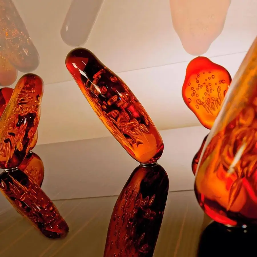 Lavish Reflex Sassi coffee table with interconnected Murano glass legs and warm orange wooden plinth supporting extra-clear glass