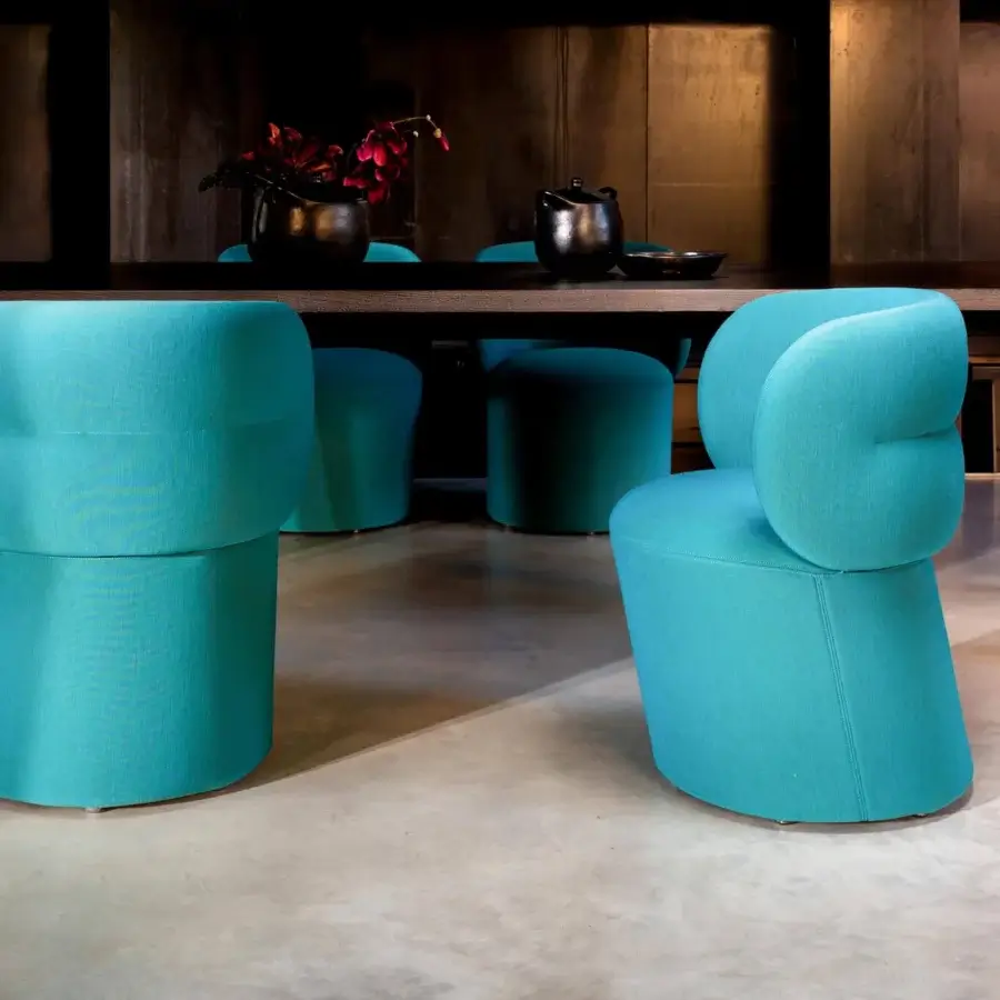 Elegant Moroso Getlucky chair with wrapping backrest and textured turquoise textile upholstery in matte finish with black painted steel base