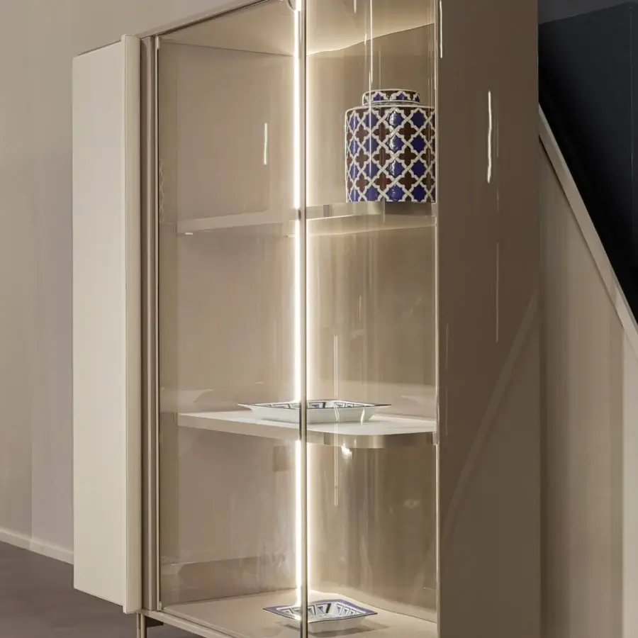 Architectural Turri Zero cupboard with glossy light beige finish, sleek metal legs and illuminated wooden shelves behind glass