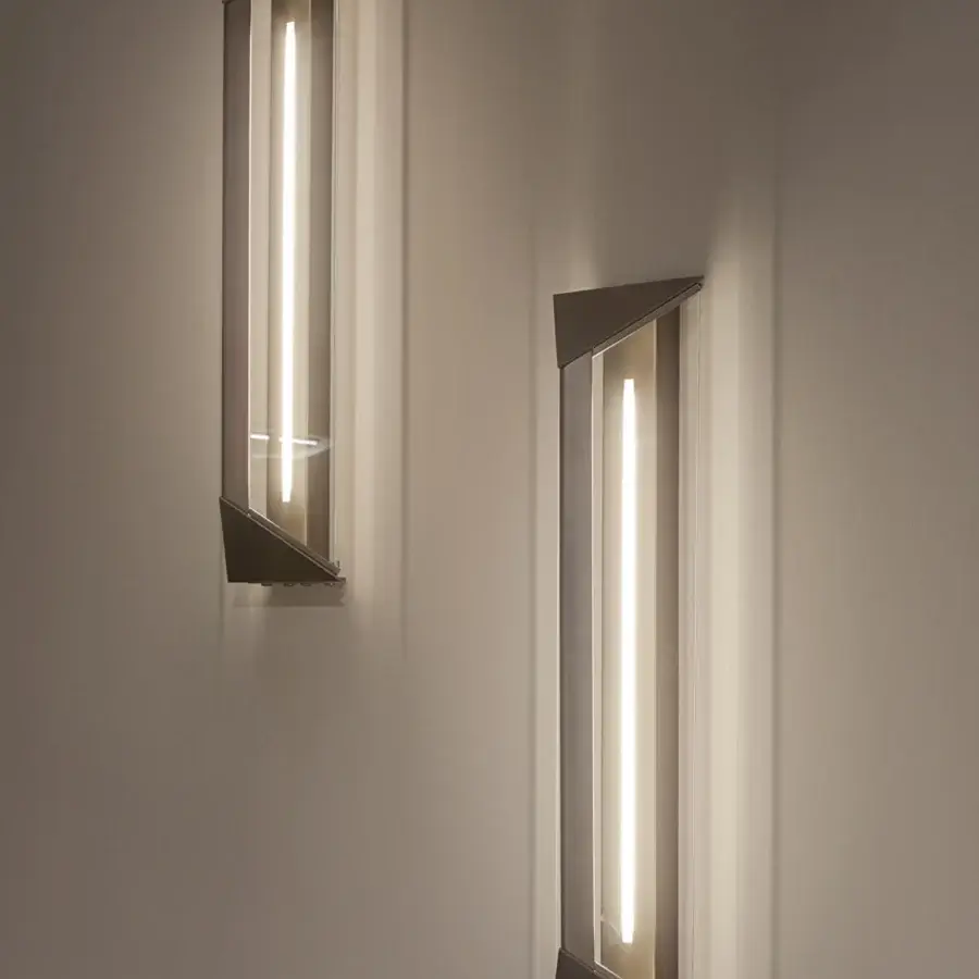 Superior Turri Zero wall lamp with a triangular metal structure and clear glass emitting bright white light