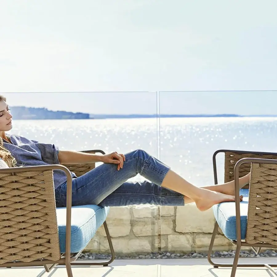 Distinguished Roberti Rattan Portofino sofa with denim blue cushions and light tan Nautic Rope woven around bronze powder-coated aluminum