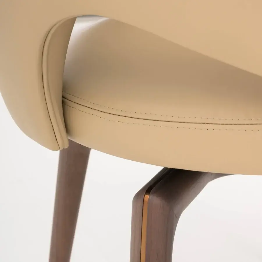 Lavish Turri Blues armchair showcases a sinuous silhouette with light beige upholstery and dark brown wood legs accented by gold inlay