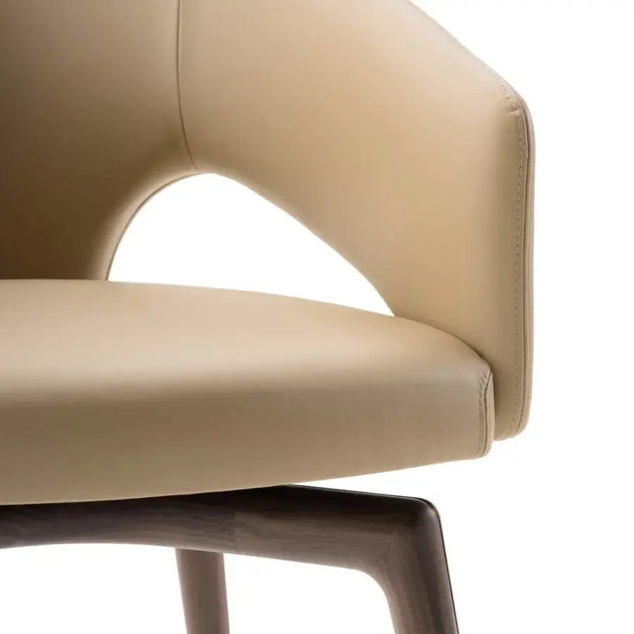 Distinguished Turri Blues armchair presents a sinuous silhouette upholstered in light beige synthetic leather with a smooth finish and dark matte wood base