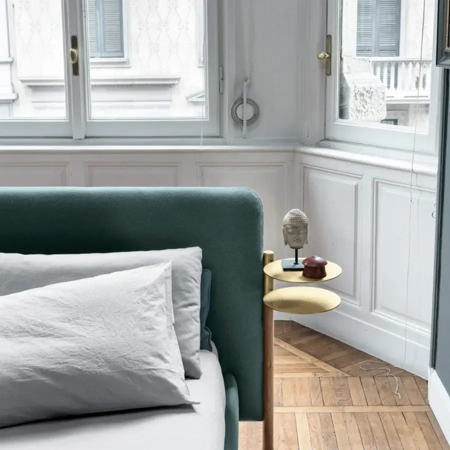 Superior Bolzan Letti Flag bed with teal textile upholstery, brass accessories and light gray linen pillows against a cushioned wood headboard