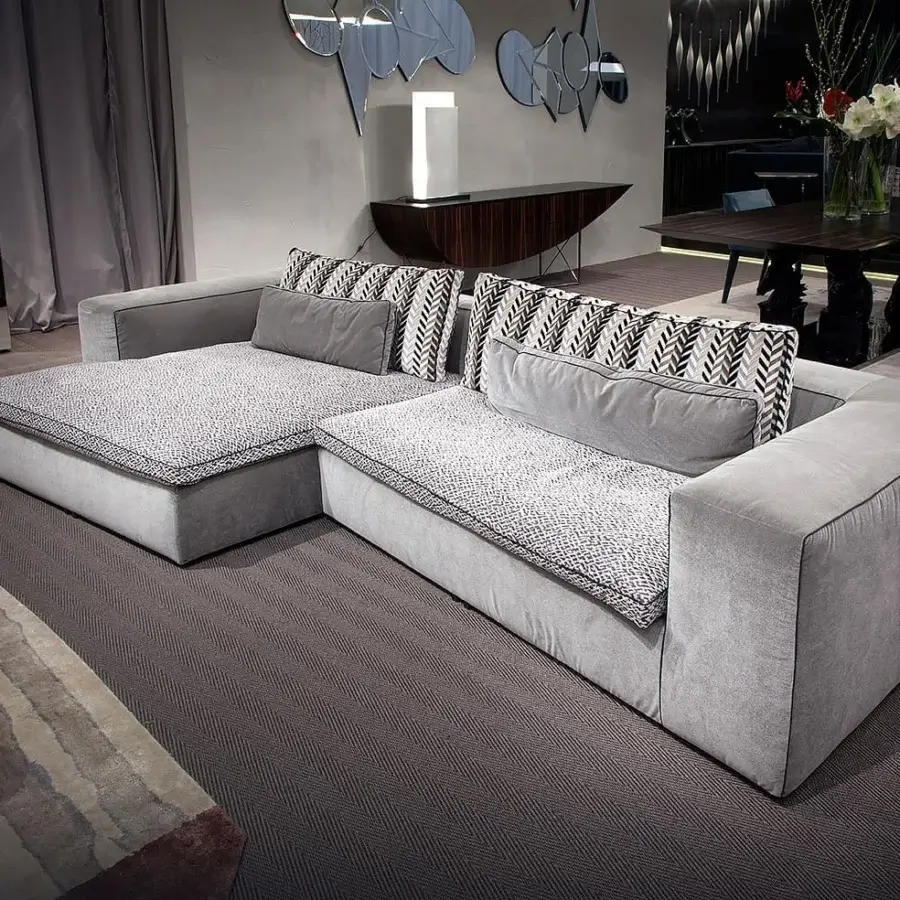 Lavish Erba David sectional with asymmetric elements upholstered in light gray textile and patterned black and white cushions
