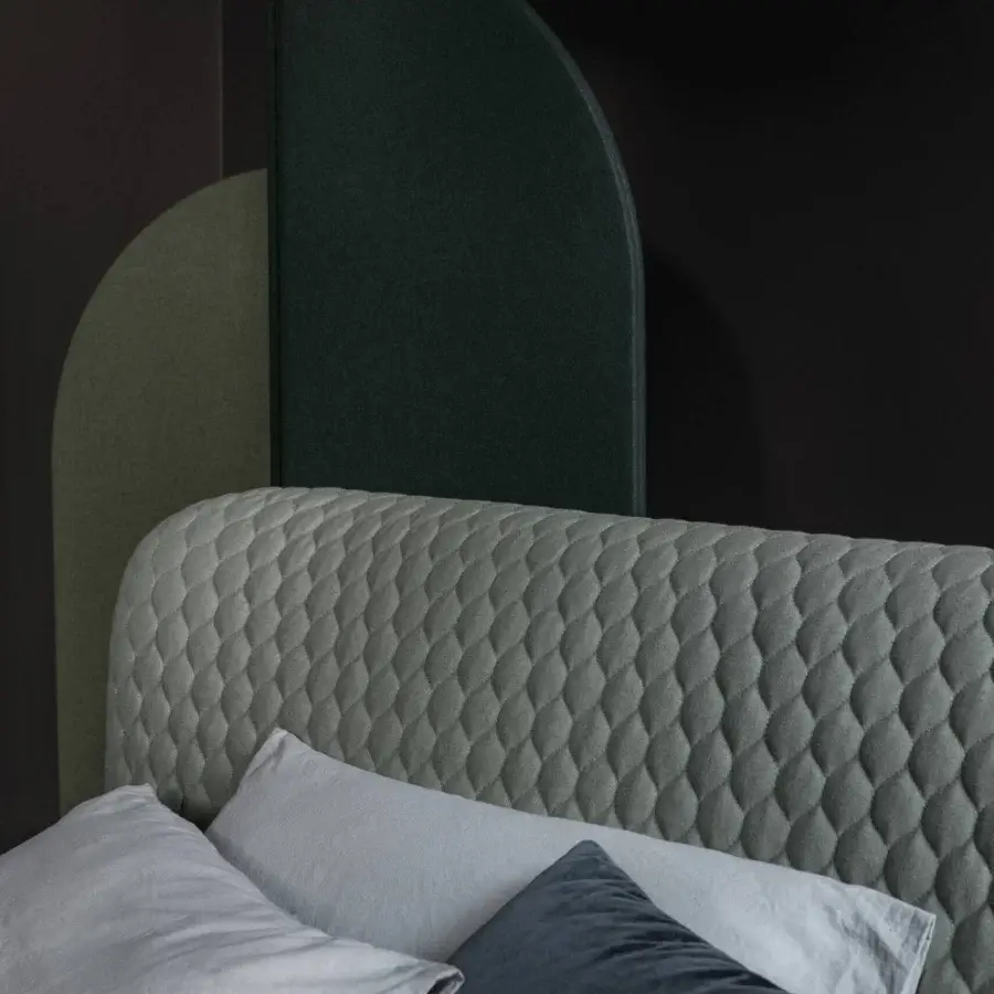 Distinguished Bolzan Letti Corolle bed with padded capitonné headboard upholstered in textured light gray textile and accent pillows