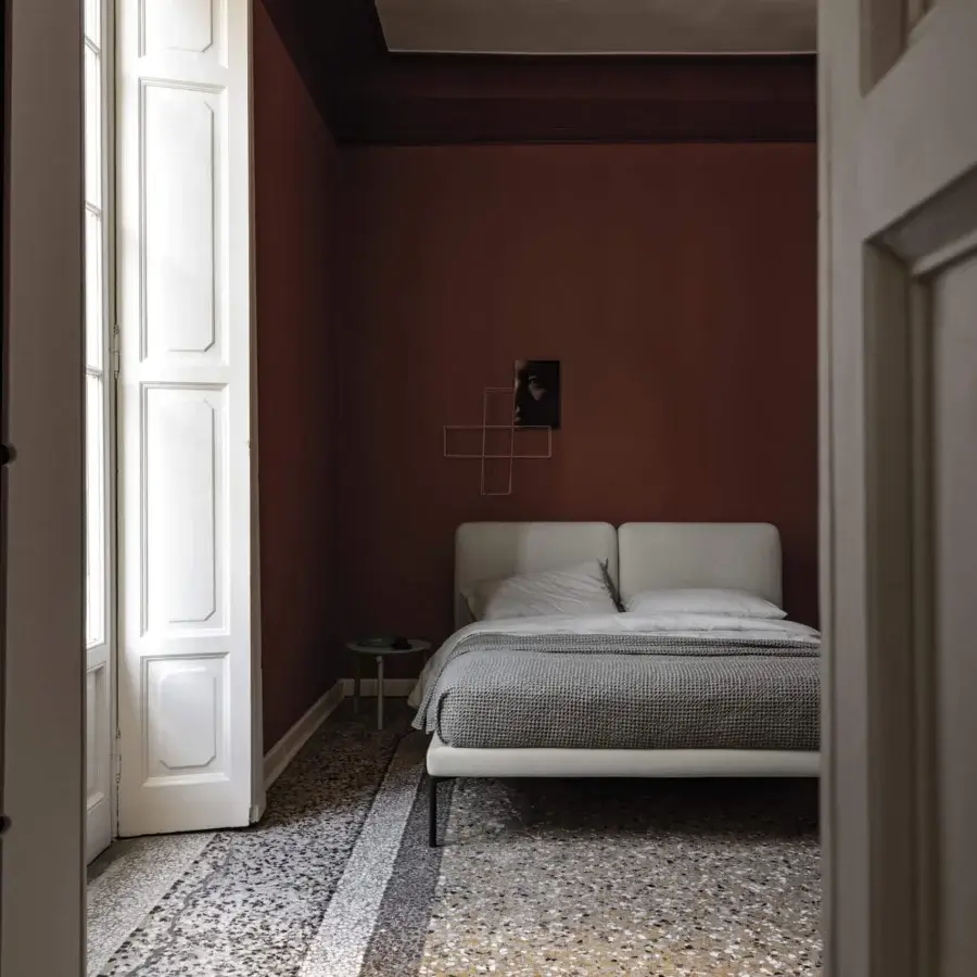 Elegant Bolzan Letti Feel bed with arched headboard upholstered in smooth light grey fabric and sleek dark metal legs