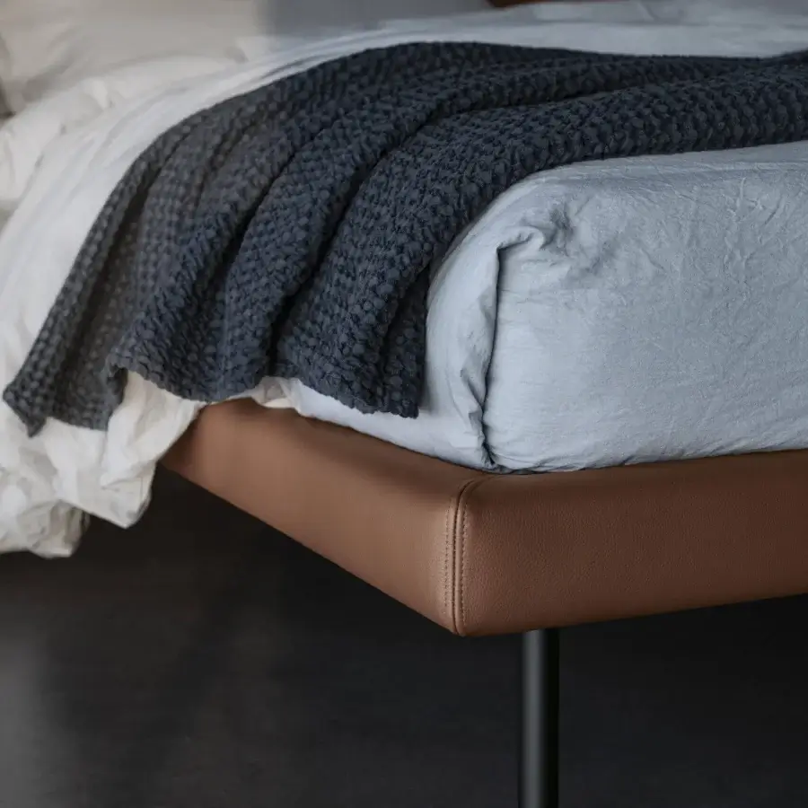 Elegant Bolzan Letti Freedom bed with smooth brown upholstery, a tufted headboard and slender matte black legs