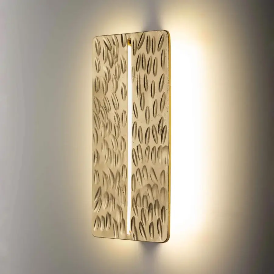 Superior Stillux Random wall lamp with a golden hammered metal frame and raised oblong shapes emitting white light