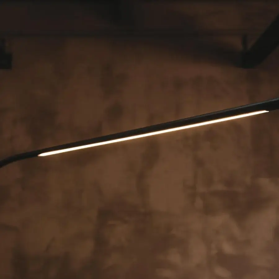 Refined Cattelan Italia Lampo floor lamp with a curved frame in graphite embossed lacquered steel illuminating with a warm glow