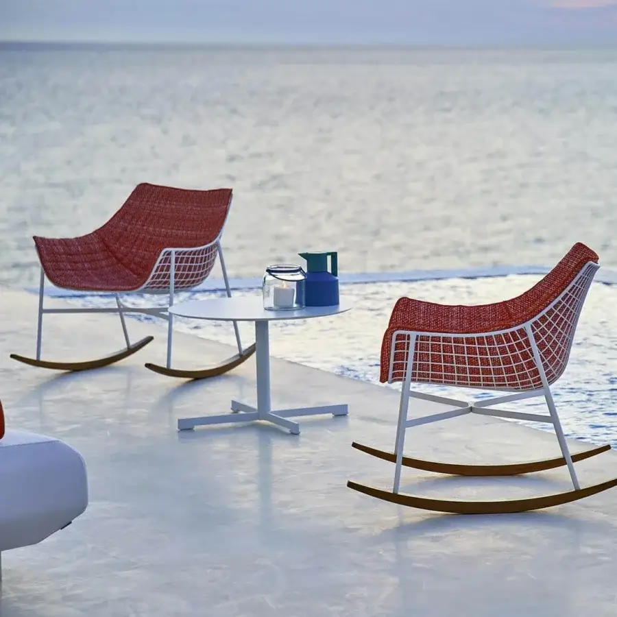 Distinguished Varaschin Summer Set rocking lounge chair with reddish-orange woven textile and teak wood runners with powder coated steel structure