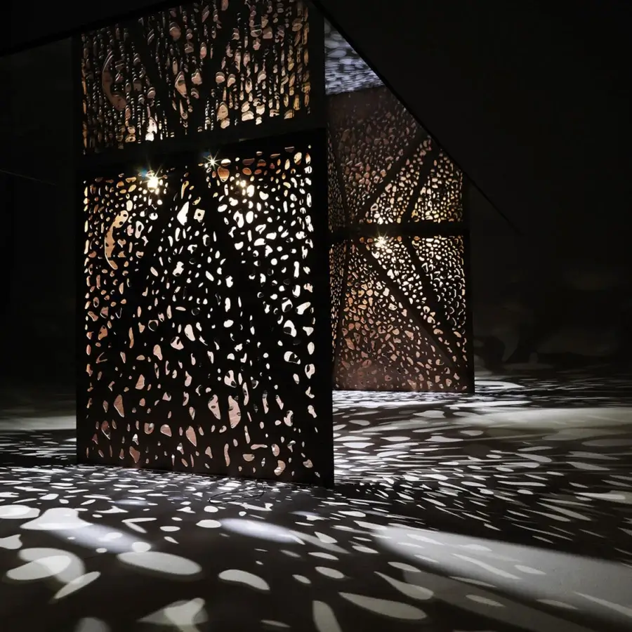 Architectural innovative table with organically perforated laser-engraved wood legs and dark matte finish crafted in Italy