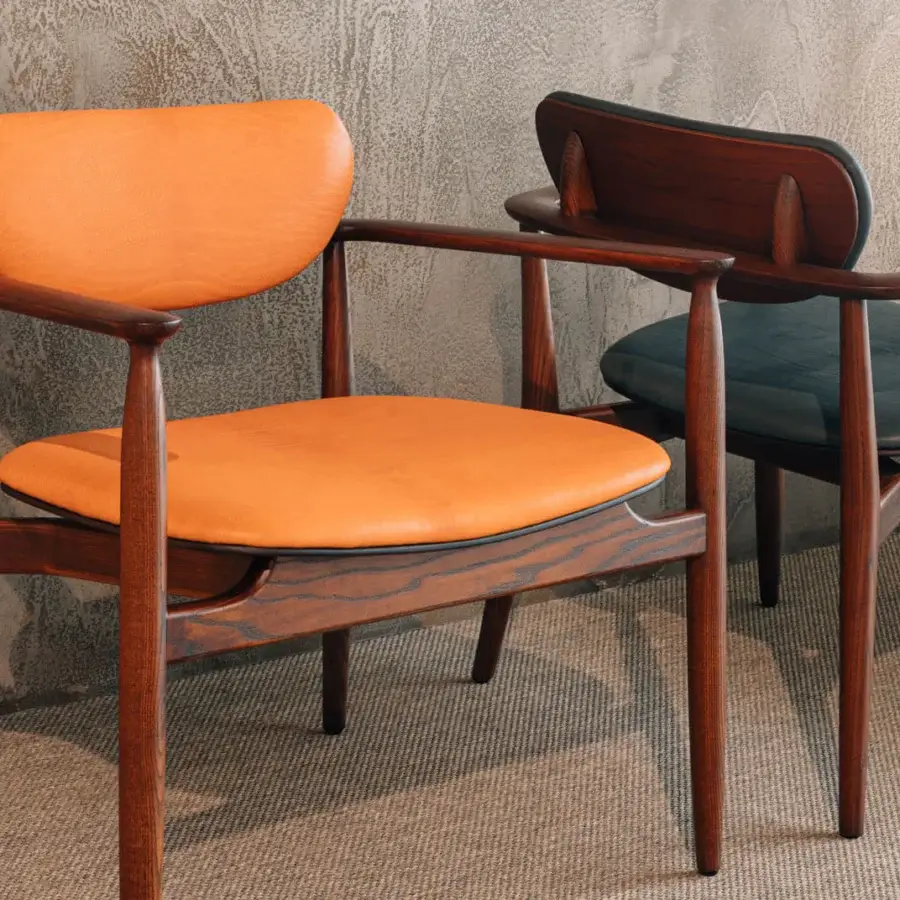 Distinguished Borzalino Regina lounge chair with fixed cushions upholstered in refined fabrics and leathers with a warm-toned wood finish