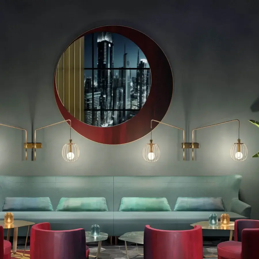 Distinguished Borzalino Eclipse mirror with a refined circular form built in treated brass partially covered in dark red material with gold accents