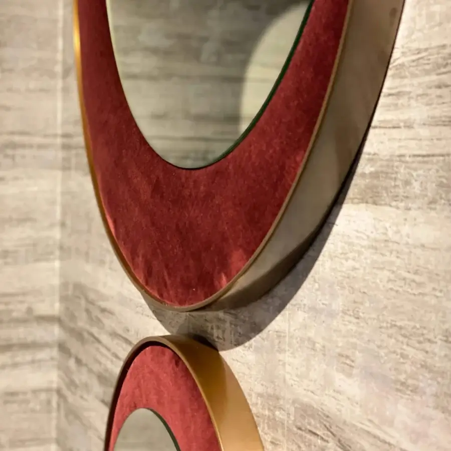 Lavish Borzalino Eclipse mirror with a refined round silhouette and treated brass metal frame wrapped in deep red velvet-like material