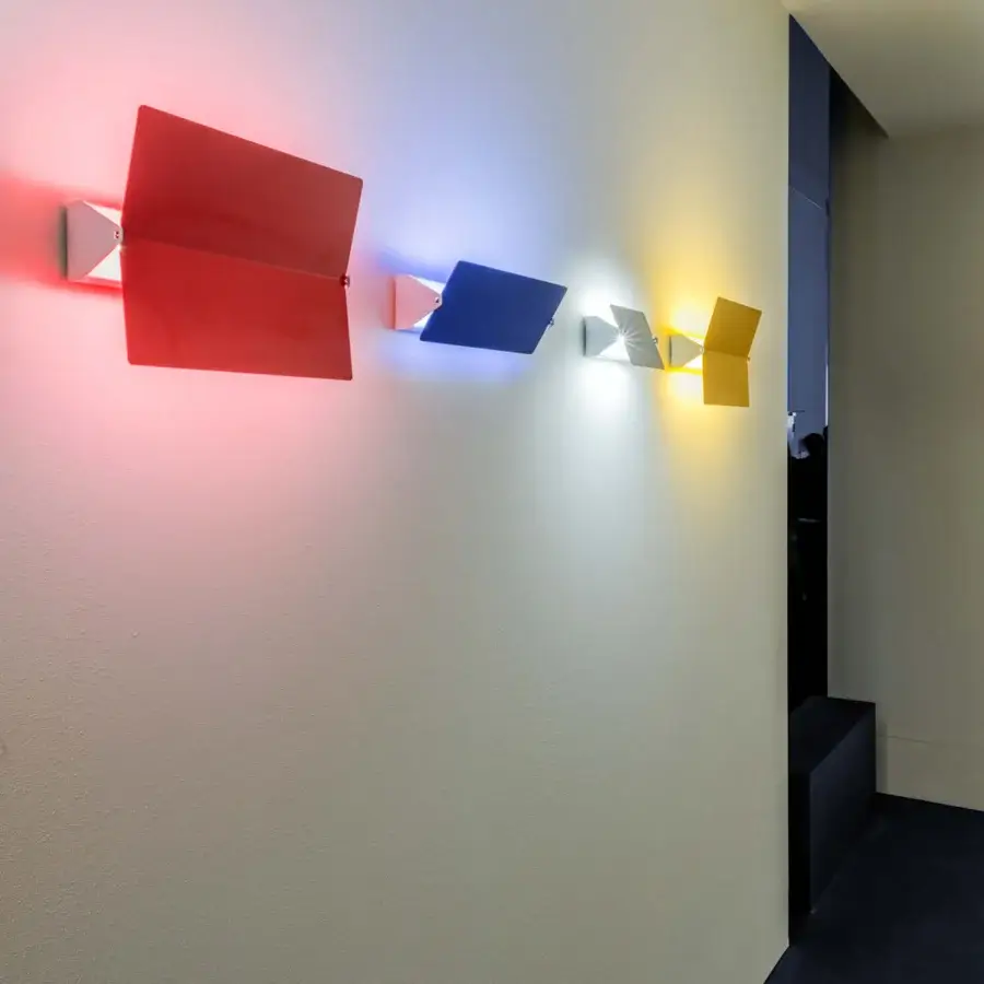 Elegant Nemo Lighting Applique à Volet Pivotant wall lamp with adjustable aluminum volet and white metal structure in red, blue, silver, and yellow hues with a matte finish