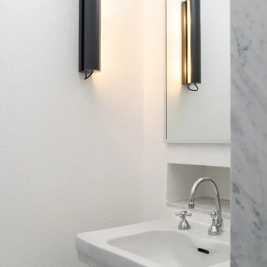 Elegant Nemo Lighting Applique Cylindrique Longue wall lamp in sleek black metal with pivoting screen controlling warm-toned light