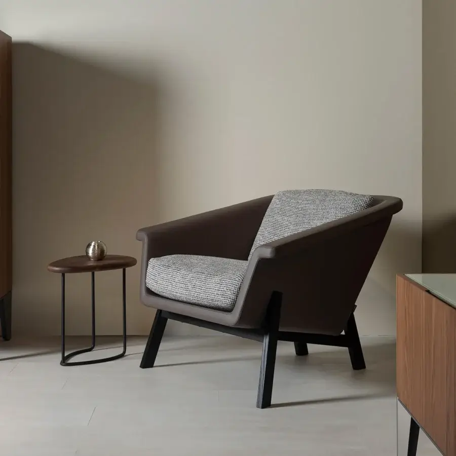 Distinguished Horm Sienna lounge chair with enveloping form upholstered in brown material and light grey textile cushions with dark wood legs