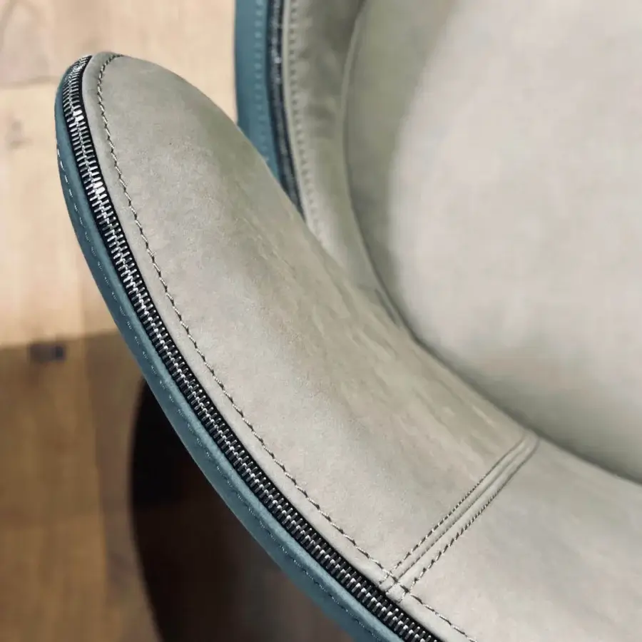 Elegant Borzalino Elektra armchair with sinuous curves upholstered in light gray textile and dark gray chromed metal zipper with a natural oak base