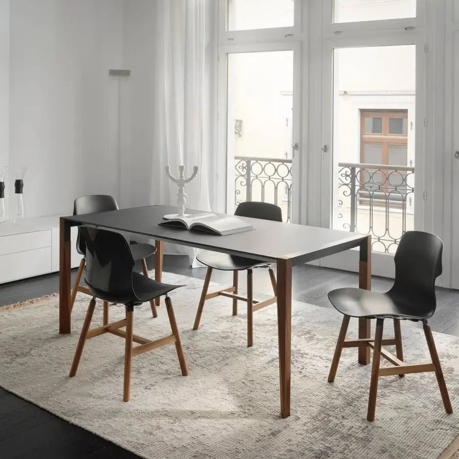 Innovative Horm Tango table with a dark matte surface and sinuously shaped natural-toned wooden legs crafted in Italy