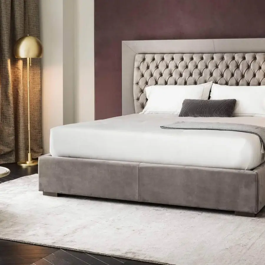 Distinguished Rugiano Kenya bed with a tufted headboard and low base upholstered in soft light gray textile exhibiting a coordinated frame