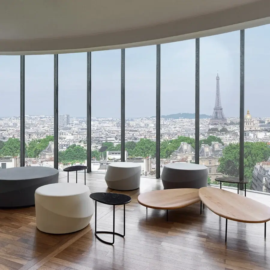 Elegant Casamania Giro ottoman presents an elongated oval shape fully upholstered in premium fabric with a smooth matte light-brown wood tabletop and dark metal legs