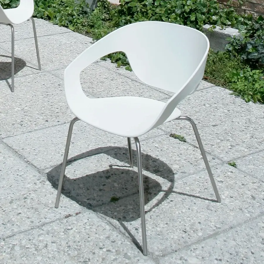 Elegant Casamania Vad armchair with curved lines and a unique backrest opening in smooth matte white reinforced polypropylene with slender polished metal legs