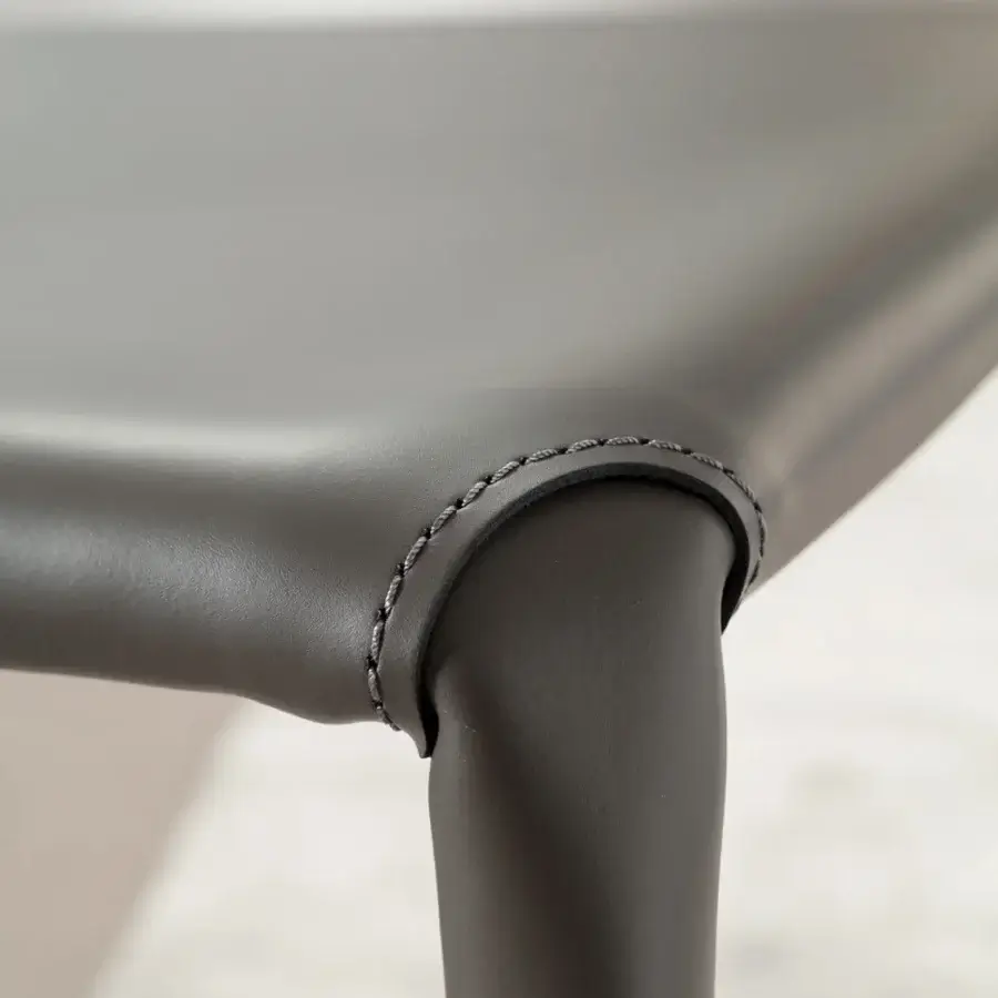 Elegant Ozzio Italia Lunette chair with dark gray leather upholstery and matching stitching showcasing a curved silhouette
