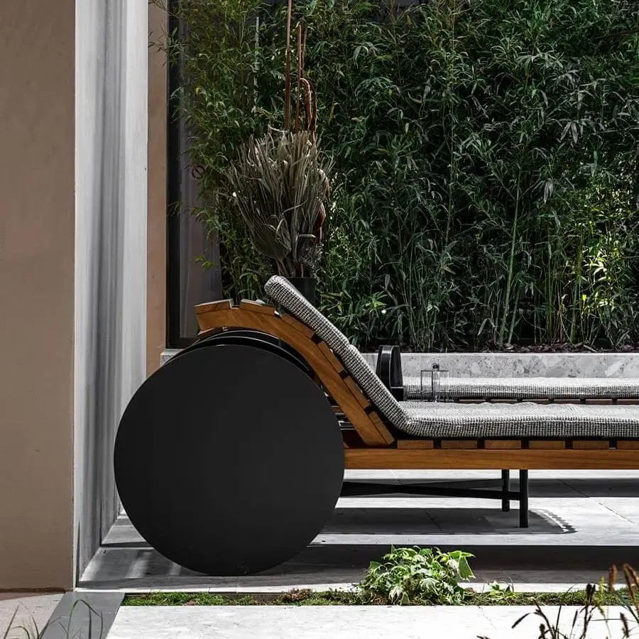 Elegant Potocco Suno lounger with Iroko wood slats, a black and white checkered padded mattress, and large HPL wheels