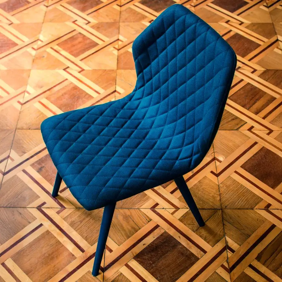 Superior Bross Ava chair with dark blue fully upholstered shell and quilted inner back, built with lacquered metal legs