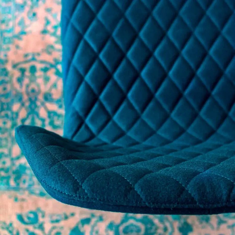 Lavish Bross Ava chair with fully upholstered teal shell, smooth quilted inner back, and wood-covered metal legs