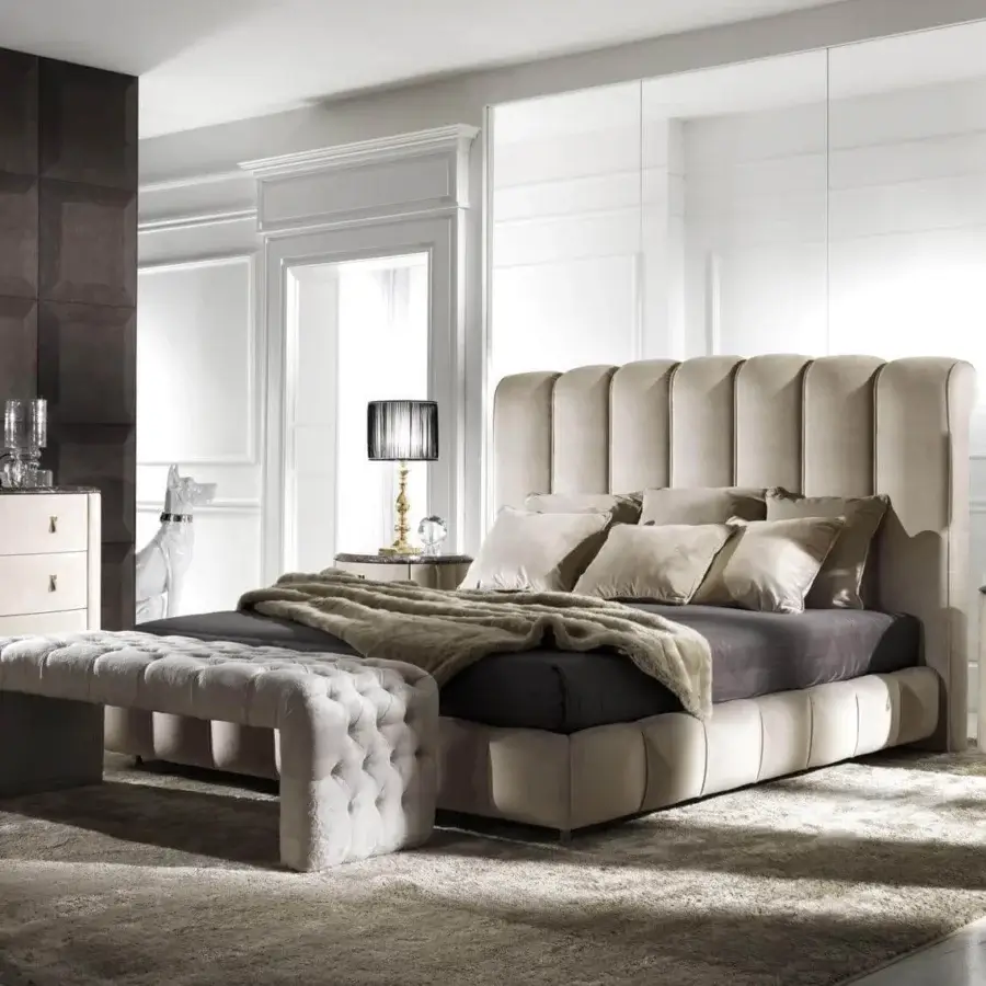 Elegant DV Home Collection Byron bed with vertically channeled light beige upholstery and a dark gray mattress with neutral throws