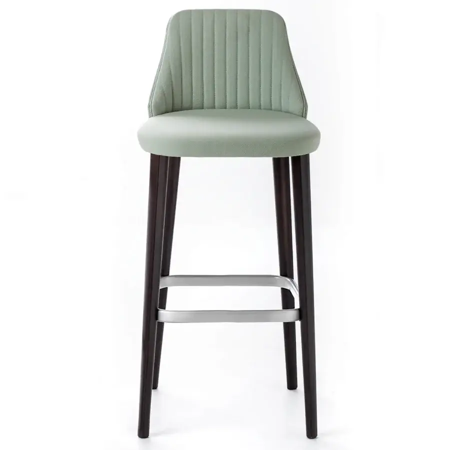 Break stool, sage green upholstery, vertical tufting, dark brown wood frame, tapered legs, metal support bar, minimalist design.