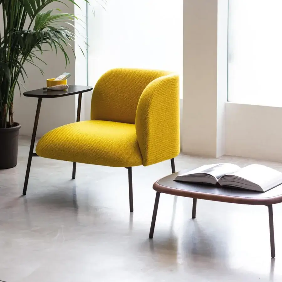 Lavish Bross Sit lounge chair with rounded form upholstered in textured yellow fabric and dark finished metal legs